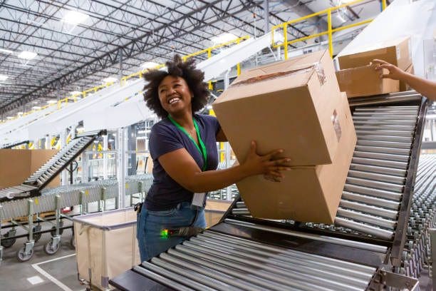 A woman holding a box on the conveyor belt.