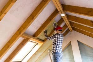 Man installing insulation in attic.